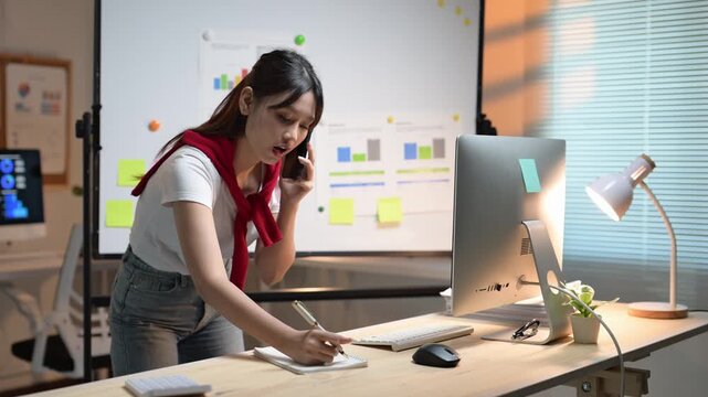 Young businesswoman taking notes while talking on phone