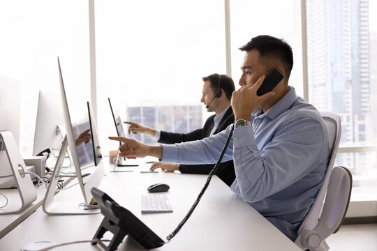 Customer support workflow. Diverse multiethnic staff of modern call center technical assistance desk telecom service centre manage real time client calls sitting by monitors in open space urban office