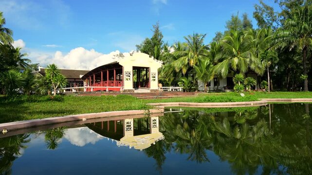 A serene covered wooden bridge at Lang Co Resort, featuring traditional Vietnamese architecture with ornate yellow gables and dragon motifs.