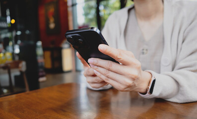 Woman holding and using a smartphone. The image highlights modern mobile communication, social media browsing, messaging and digital lifestyle.