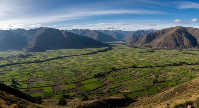 Panoramic view of the Sacred Valley of the Incas, Peru, with lush green fields and majestic mountains under a blue sky.