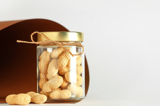 Jar with unpeeled peanuts on colorful background