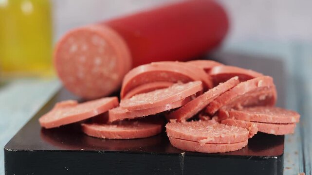 Slicing sausage on a wooden board in the kitchen