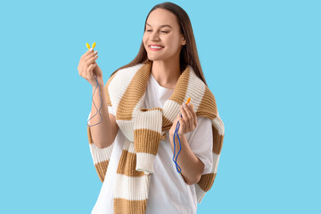Obraz premium Young woman with ear plugs on blue background