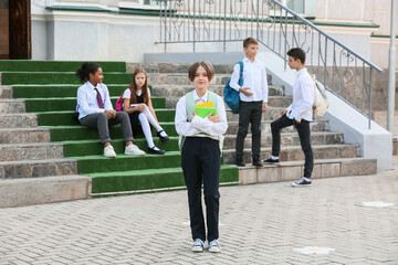 Obraz premium Cute boy and his classmates sitting on stairs near school outdoors