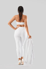 Obraz premium Stylish young woman with dreadlocks on light background, back view