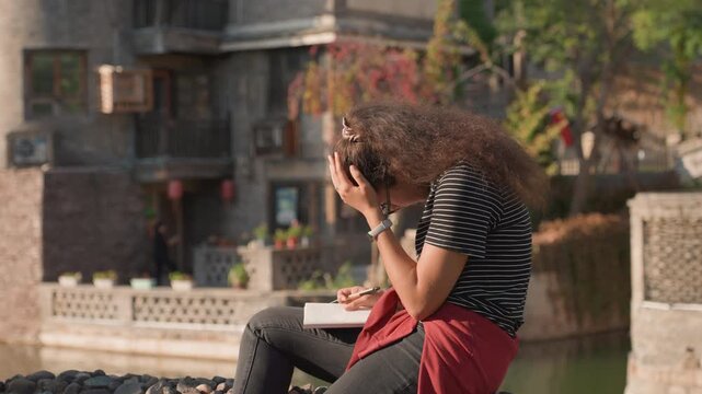 Woman crying scenery. Female tearful by riverside journal. Lady sobbing softly near water with notebook. Woman mourns silently beside flowing water while clutching her journal tightly