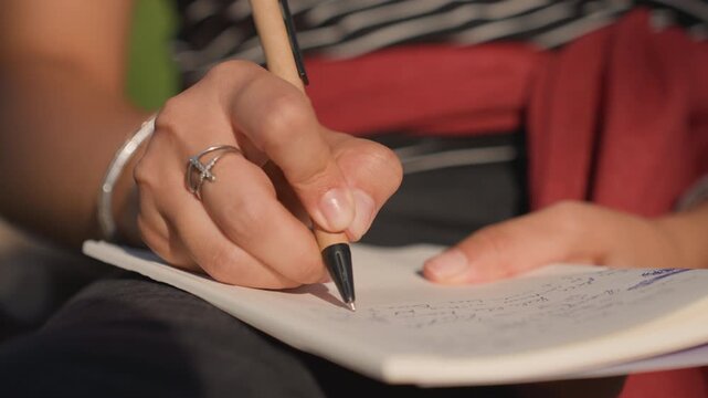 Tight closeup pen on paper, graduate student annotates research, chef records recipe variations, activist lists talking points, manager outlines tasks steady ink flow, ringed fingers, wrist bracelet,