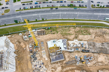 yellow crane working on under construction new multistory residential building. aerial view.