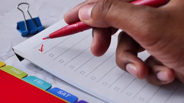 Close-up hand ticking checkboxes with red pen on a to-do list notebook, dynamic motion footage of marking tasks in daily planner, concept of productivity and organization