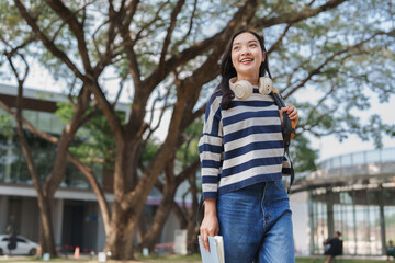 Obraz premium Smiling asian student walking on university campus