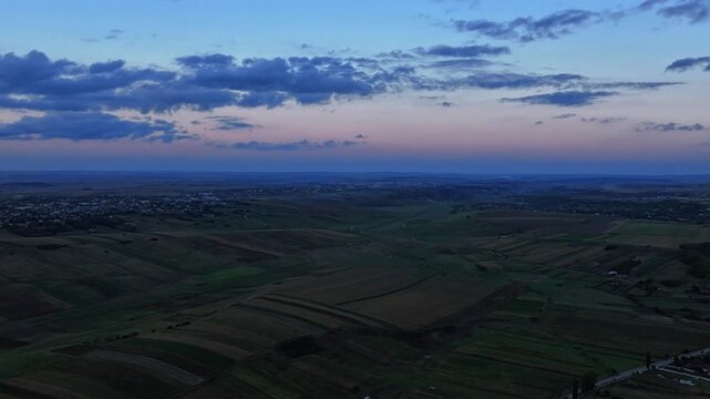 Aerial dynamic hyper lapse of Romanian skyline in blue hour, countryside agricultural fields at dusk - Botosani 4k