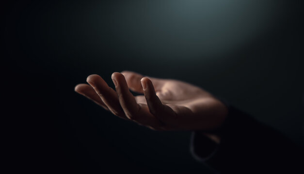 Open hand reaching in darkness. Concept of poverty, inequality, humanitarian aid