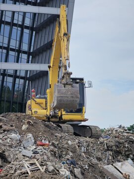 A yellow excavator is digging into a pile of trash. The scene is dirty and messy, with the excavator being the only visible object