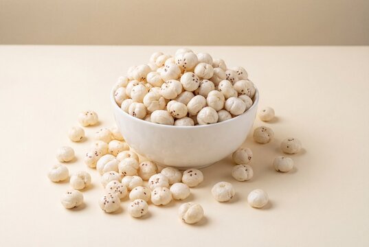 Bowl of puffed fox nuts phool makhana overflowing on a plain beige background