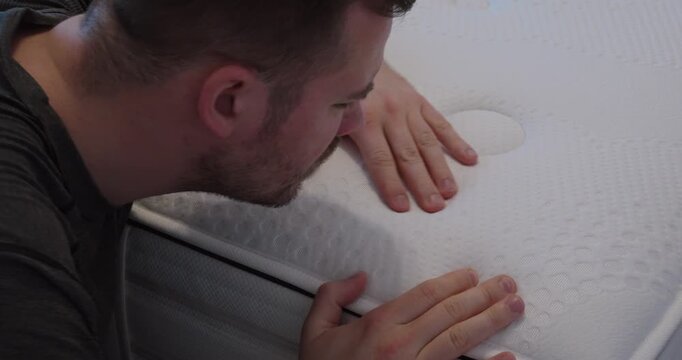 Close-up of a man carefully examining and pressing a mattress surface, highlighting material quality, comfort testing and consumer buying decision concepts.