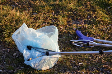 Litter pickup tool. Trash grabbing tool.Volunteers cleaning up trash in nature. © Broker_Aleksandr