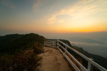 Obraz premium Adventurous traveler standing on a mountain peak viewpoint enjoying a spectacular sunrise and sea of clouds.