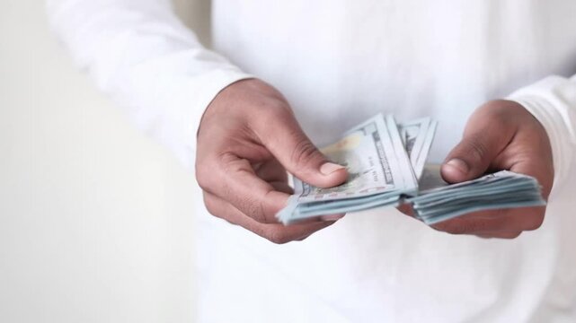 Hands counting stack of one hundred dollar bills in slow motion