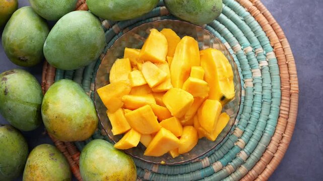 Freshly cut mangoes displayed on woven mat with whole mangoes surrounding