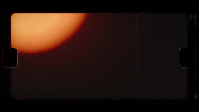 Vintage film frame with warm orange light bleeding and scratches. Black background, rounded corners