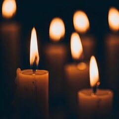 Warm glow of multiple lit candles in darkness