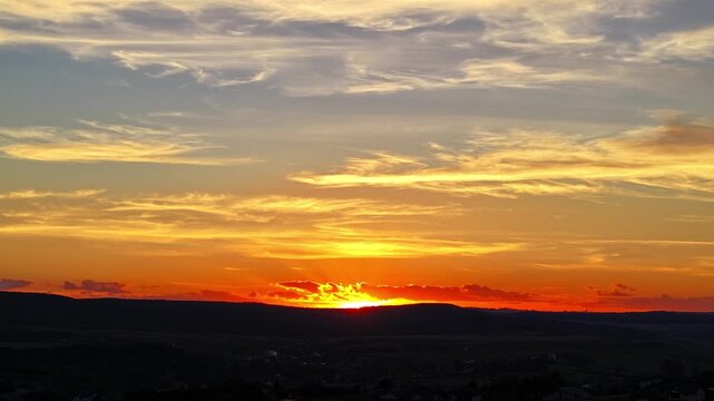 Aerial hyper lapse of fiery sunset, glowing golden sun hiding behind the hill - Botosani, Romania