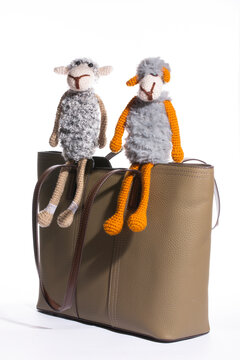 Women's beige leather bag with a toy on a white background