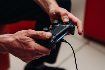 black gamepad in hands, adult man playing game console, selective focus © Anton Pentegov