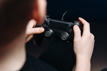 black gamepad in hands, young boy playing game console, selective focus © Anton Pentegov