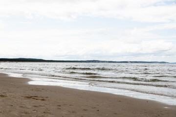 Peaceful summer beach with soft surf and distant coastline