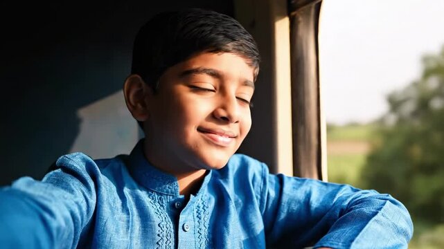 smile boy - Young boy in a blue kurta gazes out a train window, warm sunlight illuminating his thoughtful smile as blurred green landscape drifts by, evoking quiet travel daydreams and wonder