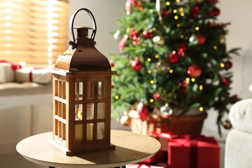Beautiful Christmas lantern on wooden table indoors, space for text. Bokeh effect