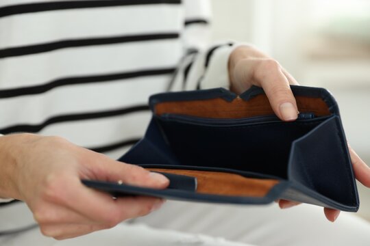 Woman with empty wallet against blurred background, closeup
