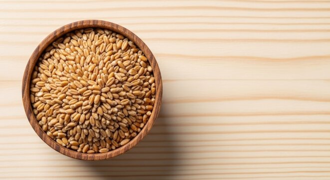 A wooden bowl filled with wheat kernels on a wooden table.