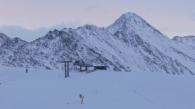 Drone shot of the Krimml ski lift moving in front of towering snow-covered mountains, using a parallax effect to emphasize depth and layered alpine winter scenery in Austria.