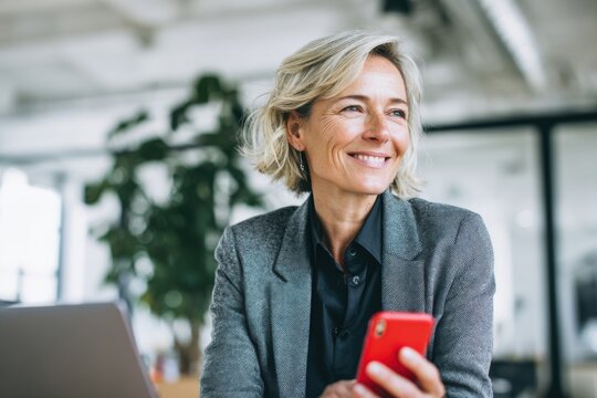 Smiling woman holds phone at work. Modern professional, happy and successful.