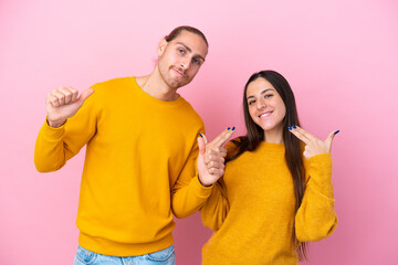 Obraz premium Young caucasian couple isolated on pink background proud and self-satisfied in love yourself concept