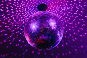 Fototapeta premium disco ball with mirror surface and bright rays, purple color, hanging on ceiling, night party background