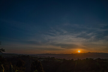 A breathtaking sunset over layered mountain ranges, with warm golden light fading into a deep blue sky, creating a serene and expansive natural landscape ideal for travel and nature themes. © Narong Niemhom