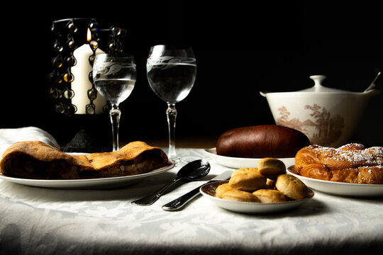 Mesa de comida mallorquina con espinagada, sobrasada, enseimada y galletas, con iluminaci&oacute;n de vela.