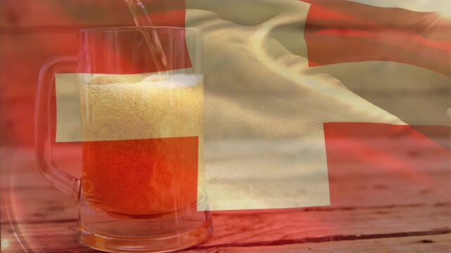 Pouring stream upper-left, amber beer filling mug, foam rising, red cross flag rippling to fill mug