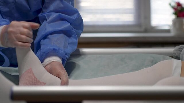 Doctor Examining Patient Foot After Brace Removal. Medical professional examining a patient foot and ankle, which is covered in a white compression stocking, following the removal of a stabilizer