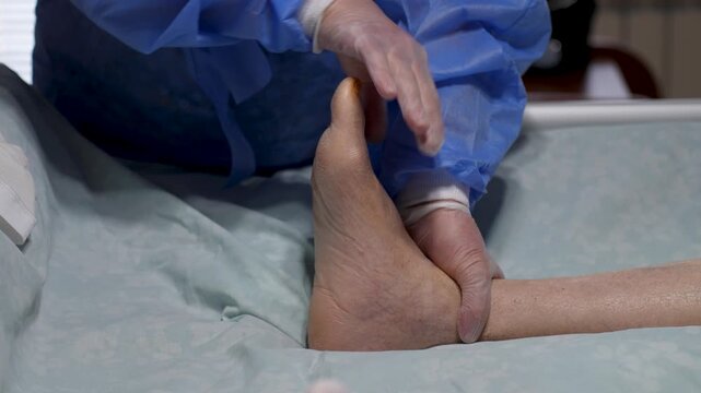 Physician Examining Bare Ankle After Surgery. Medical professional performs a physical examination of a patient's bare ankle and foot following the removal of all orthopedic supports.