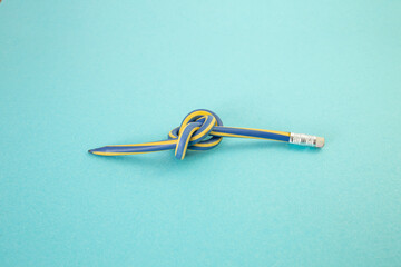 Flexible pencil crayon knot on bright blue background study stress concept