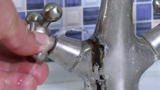 A damaged faucet on the washbasin is checked by a plumber with a water faucet in the bathtub. 4k video