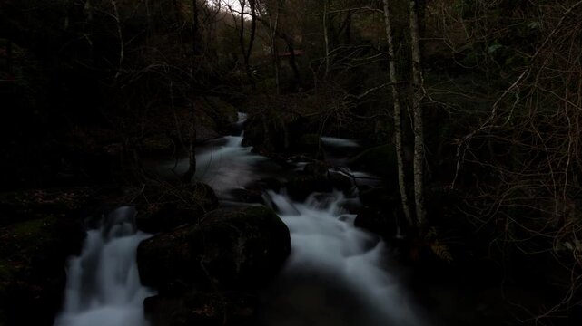 Timelapse of a mountain river throught the stones in the middle of a forrest.