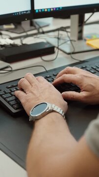 Close-up of hands typing on a computer keyboard at a modern workstation with multiple monitors, illustrating office work, data entry and professional digital workflow.