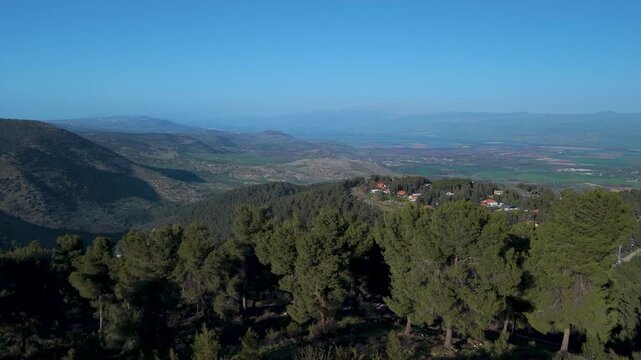 Biriya Forest and Amuka village landscape during a wide aerial pan overlooking Hula Valley and Golan Heights in Israel.