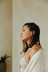 Fototapeta premium Portrait of woman with braids in white top, eyes closed